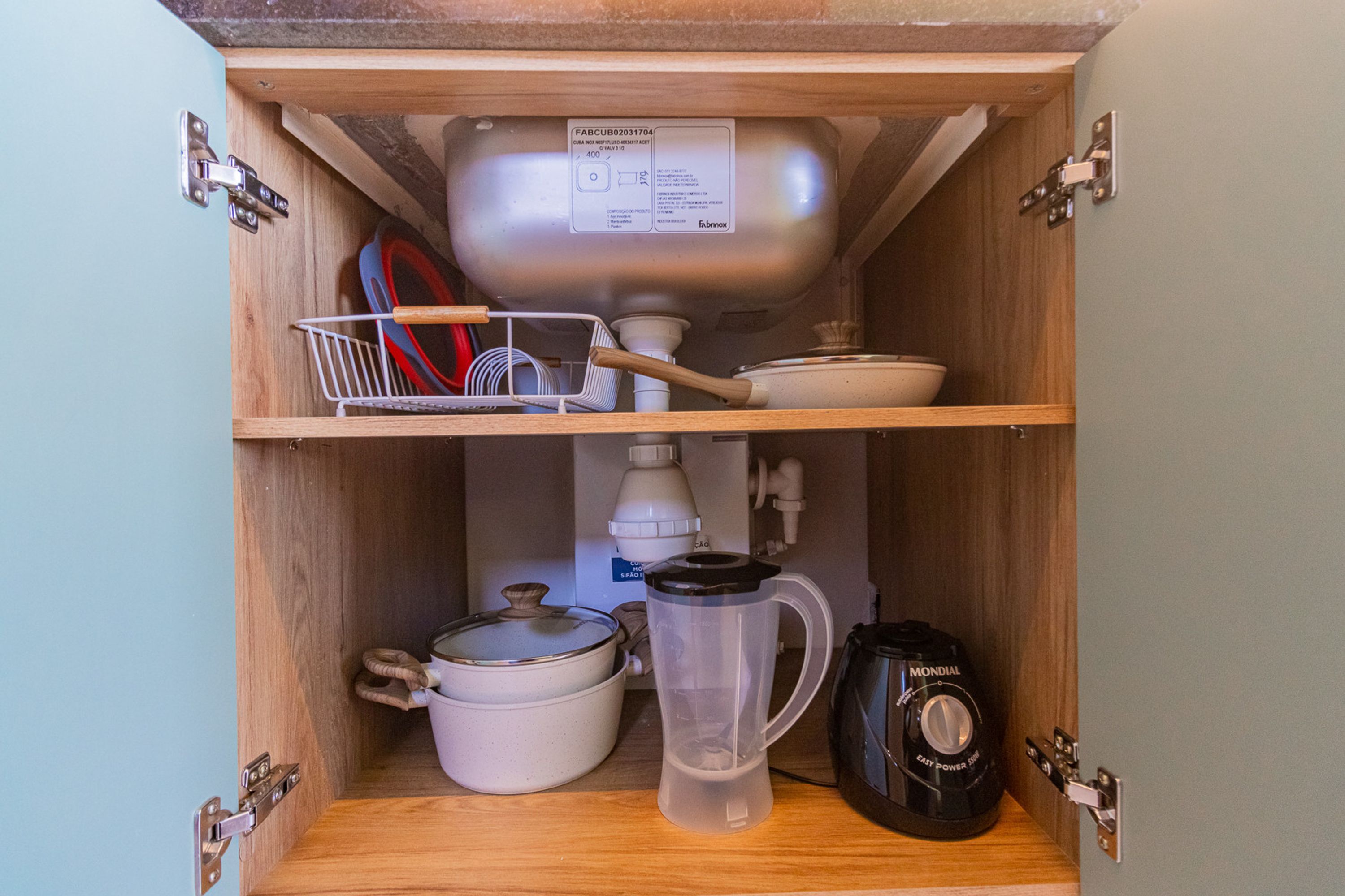 A kitchen cabinet with a built-in sink, a dish rack, a kettle, a blender, and a coffee maker.