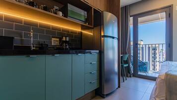 Una cocina moderna con refrigerador empotrado, cafetera y microondas. Hay un balcón con vistas a la ciudad.