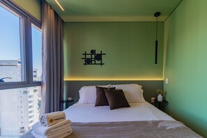 A hotel room with a bed, a nightstand, a wall-mounted light fixture, and a window with curtains. - Cozy Apt With Balcony Vila Clementino SP - Sp-l1502 (São Paulo)