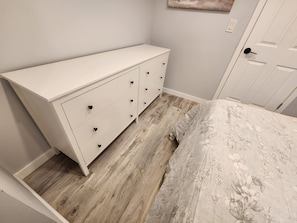 Ein Schlafzimmer mit weißem Schminktisch, einem blumigen Bettbezug und Holzboden.