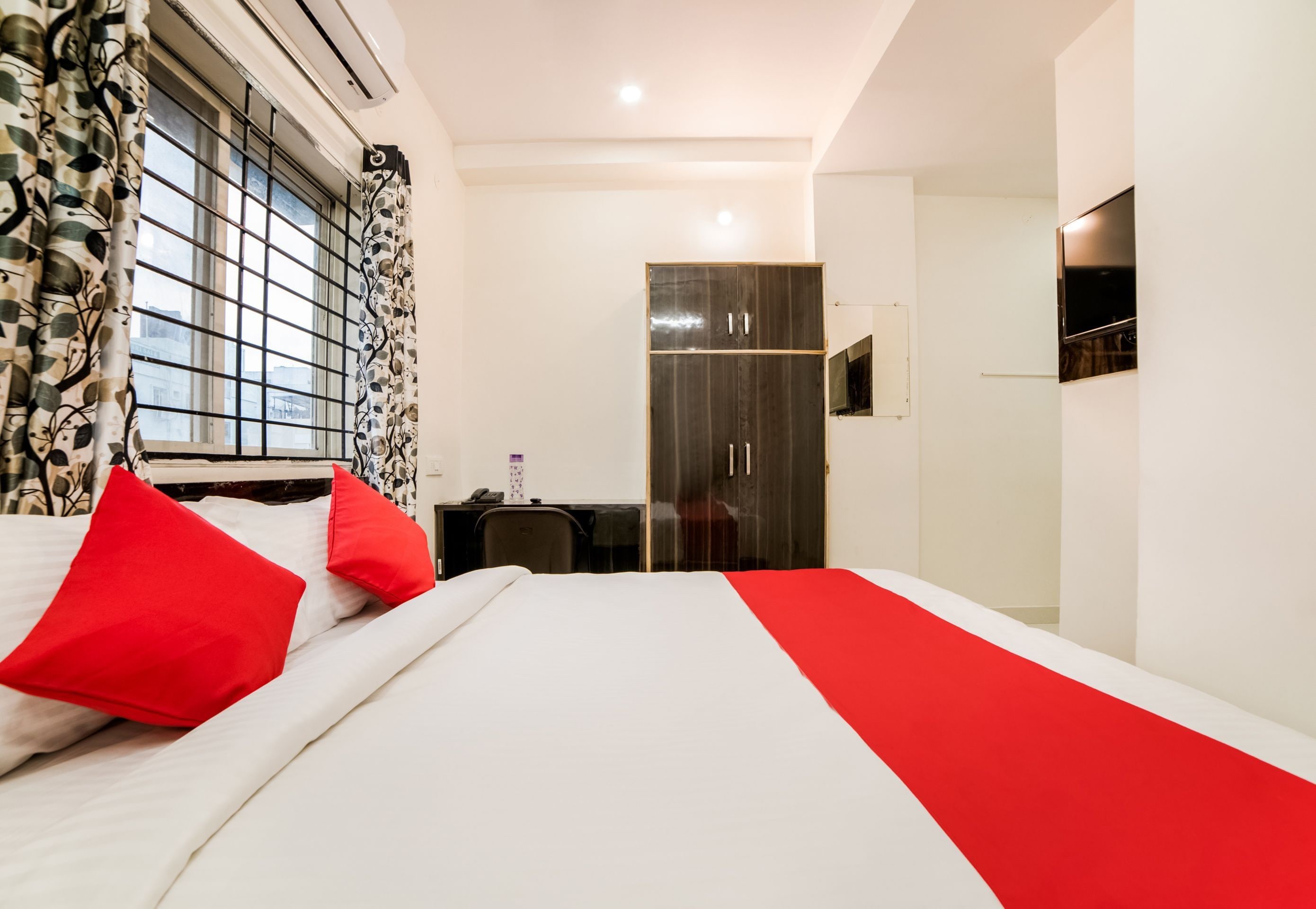 Una habitación de hotel con una cama, un escritorio, un armario y un televisor.