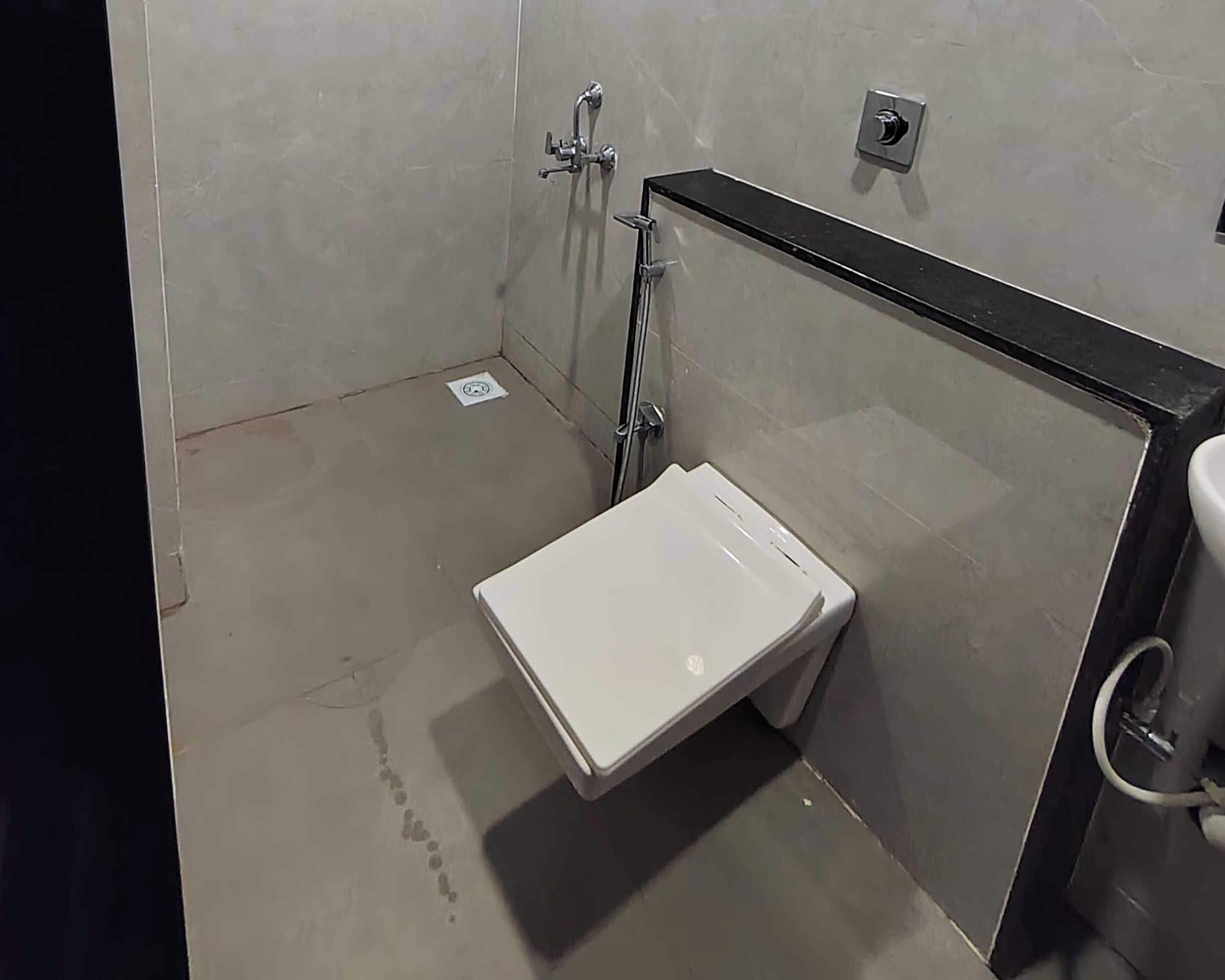 Un baño pequeño y cerrado con inodoro blanco, zona de ducha y lavamanos.