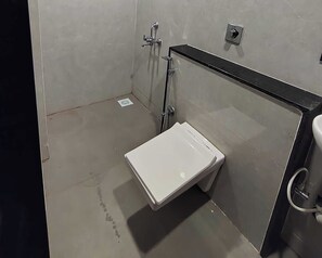Un baño pequeño y cerrado con inodoro blanco, zona de ducha y lavamanos.