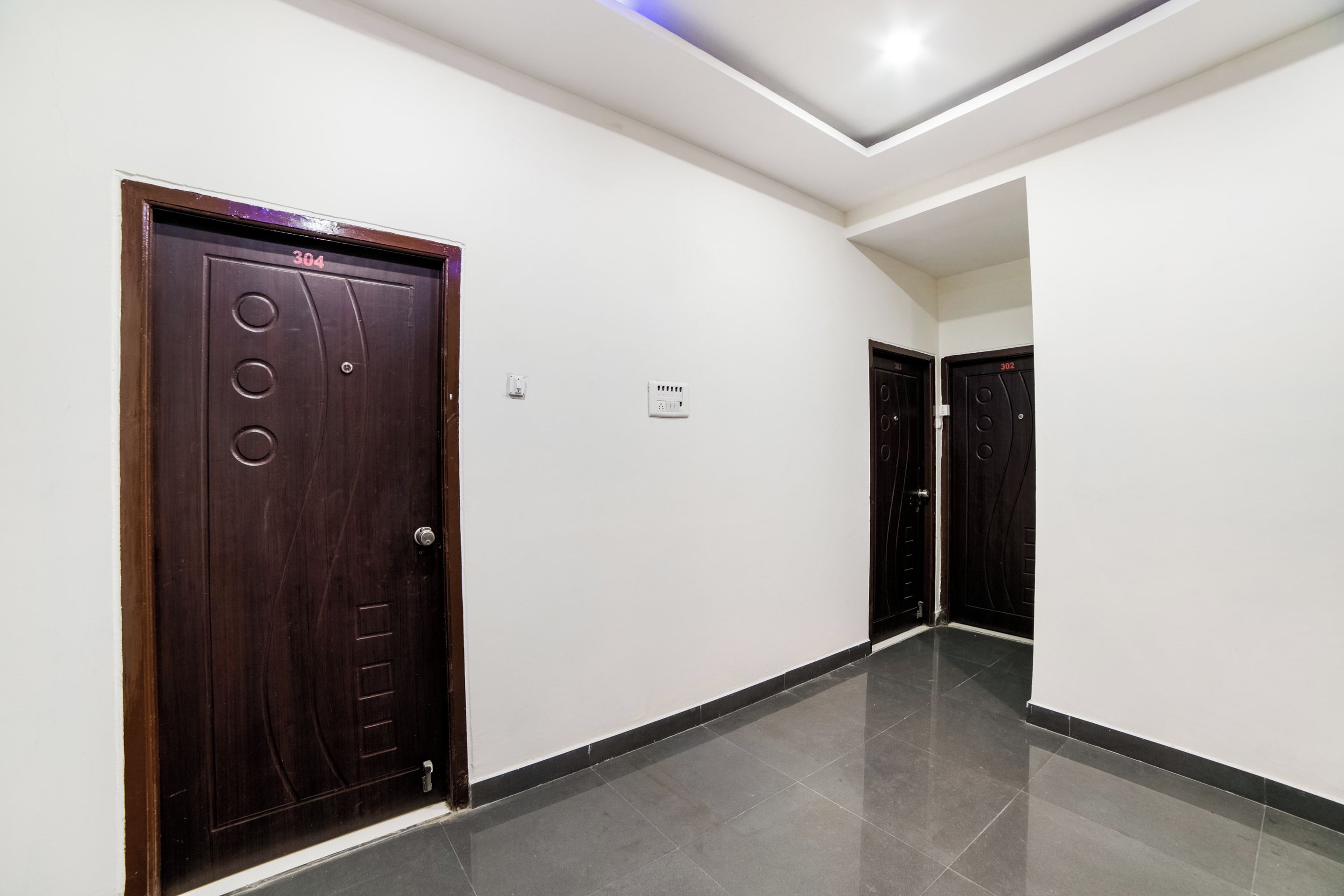 A corridor with two dark wooden doors, one marked with the number 304 and the other with 302.