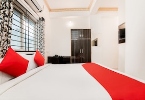 Una habitación de hotel con cama, armario, escritorio y espejo.