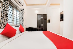 Ein Hotelzimmer mit Bett, Schreibtisch, Kleiderschrank und einem Fenster mit Vorhängen.