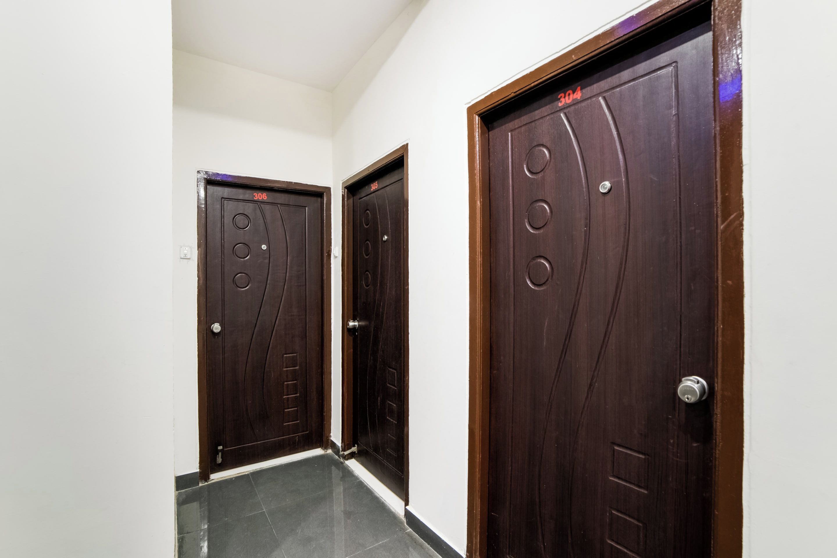 Un pasillo con dos puertas de madera oscura, cada una con un número sobre el pomo.