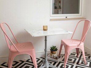 A room with a white marble table, two pink chairs, a small potted plant, and a window with a view. - Romantic Holiday Retreat in Manzanares (Manzanares)