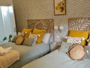A hotel room with two beds, patterned wallpaper, a decorative headboard, and a bedside table with lamps. - Romantic Holiday Retreat in Manzanares (Manzanares)