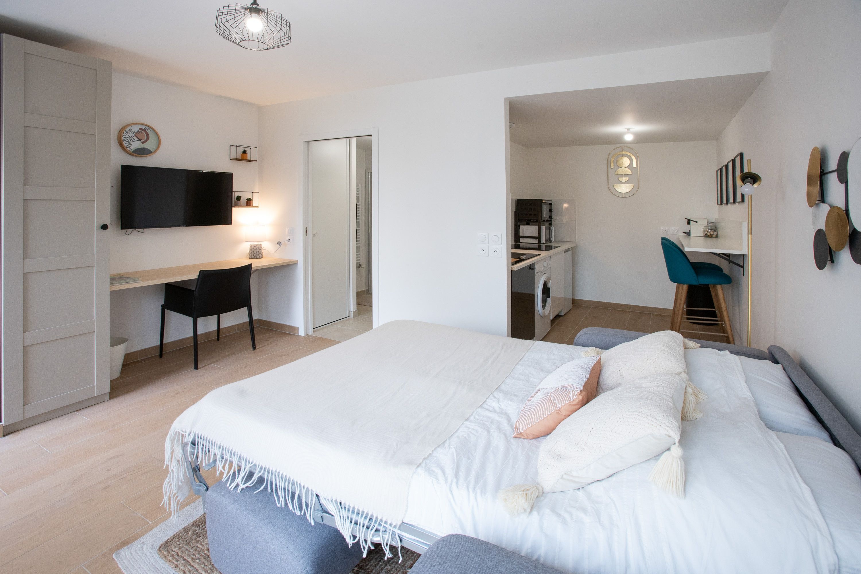 Een moderne slaapkamer met een bed, een bureau en een televisie.