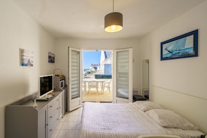 Une chambre à coucher avec un lit, une télévision, un bureau et une vue sur l’extérieur.