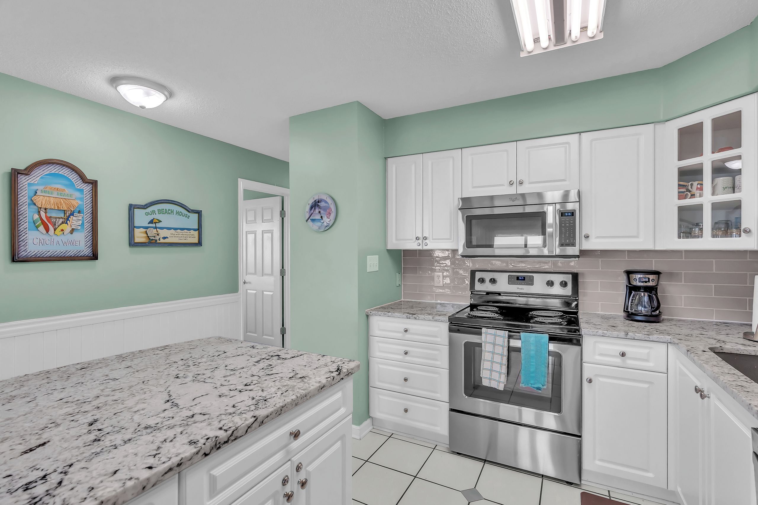 A kitchen with white cabinets, a stainless steel stove, and a microwave.