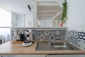A kitchen with a wooden countertop, a coffee maker, a sink, and patterned tiles. - Le Saint Lambert - studio au cœur de Troyes (Troyes)