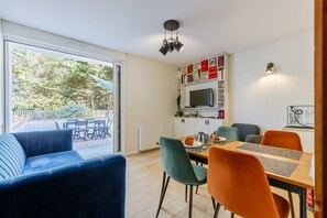 Ett modernt vardagsrum med en matplats, en soffa och en tv som är monterad på väggen.