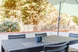 Ein Terrassentisch mit Stühlen, einer Tischauflage und einem Metallschirm.