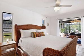 Ein Schlafzimmer mit einem großen Bett, einem Nachttisch, einem Fenster und Blick ins Freie.