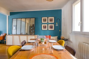 Ein Esszimmer mit einem Holztisch, gedeckt für vier Personen, Stühlen, einem Spiegel und gerahmten Bildern an der Wand.