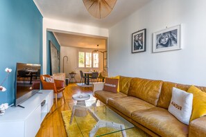 Ein modernes Wohnzimmer mit einer Ledersofa, einem Glastisch und einem Essbereich im Hintergrund.