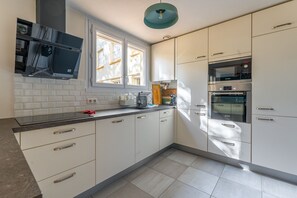 Eine moderne Küche mit weißen Schränken, einem Bosch-Ofen und einem Fenster mit Jalousien.