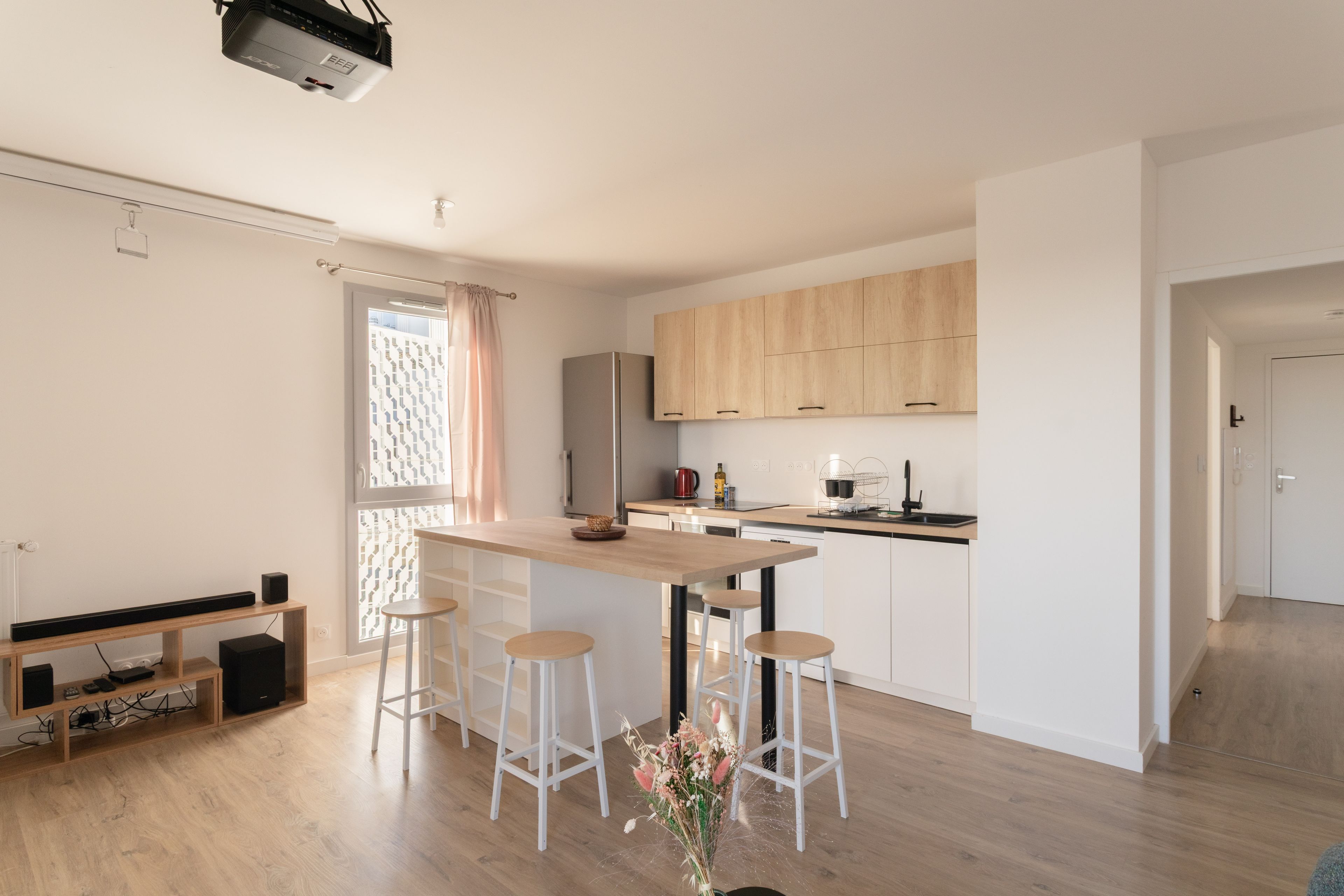 A modern kitchen with wooden cabinets, a built-in oven, and a bar area with stools.