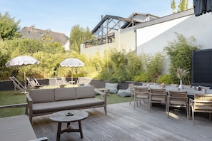 Eine Außenpatio mit einer Couch, Stühlen, einem Tisch und Sonnenschirmen.
