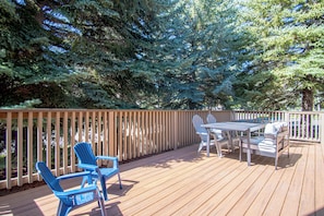 A wooden deck with a table and chairs, surrounded by trees. - Elkhorn Bluff Ground-floor 3BR Condo + Complex & Resort Amenities (Sun Valley)