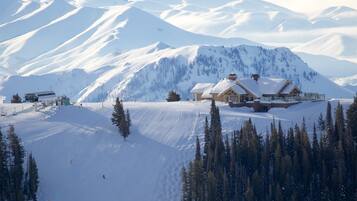 A snow-covered mountain with a lodge featuring a wooden exterior and a ski lift in the background.