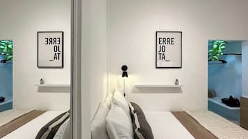 Un dormitorio moderno con dos camas, un espejo y dos luces fijadas a la pared.