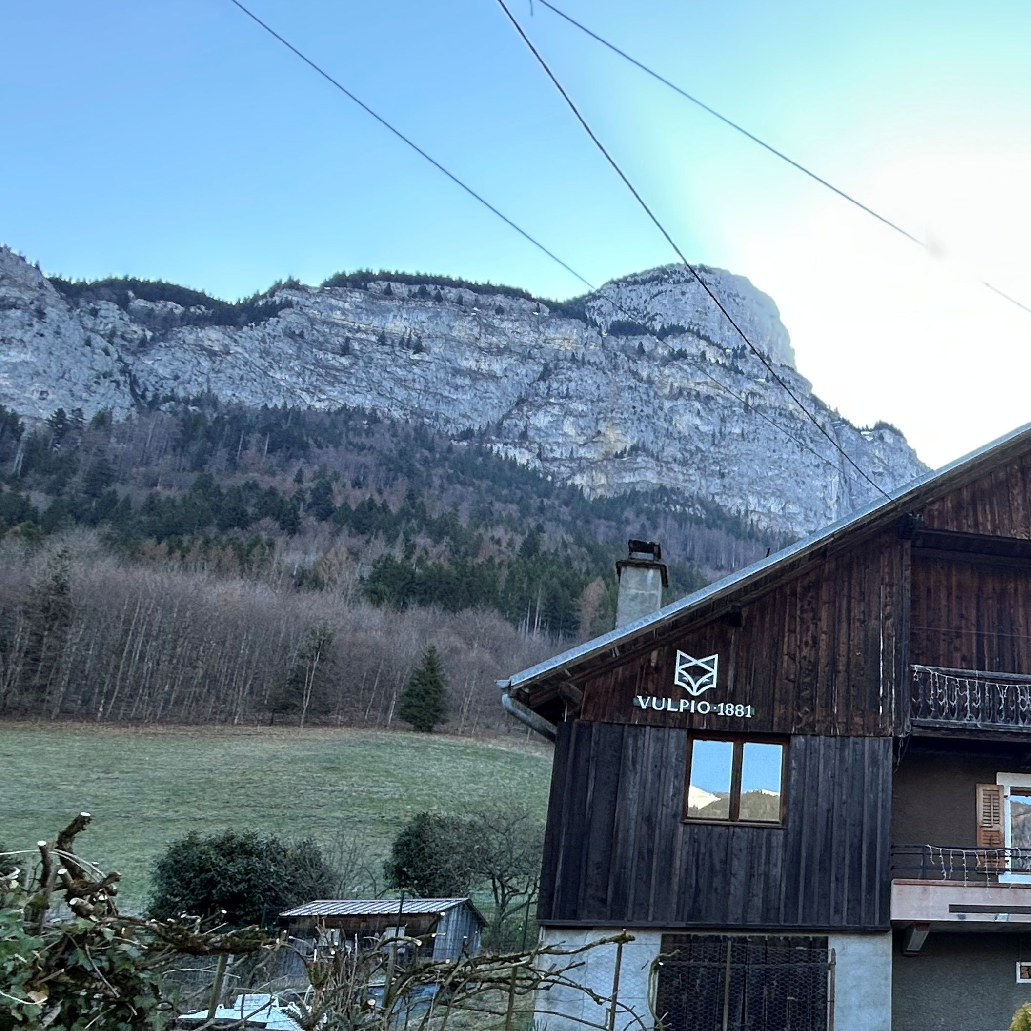 A wooden building with a sign reading 'VULPIO 1881' and a mountainous backdrop.