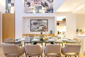 A dining area with a glass table, chairs, and a large abstract painting above. - Genteel Home Reyes Catolicos Sevilla (Seville)