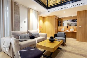Ein modernes Wohnzimmer mit Sofa, Couchtisch und einem Essbereich mit Küche im Hintergrund.