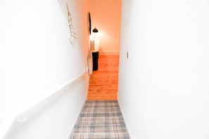 A narrow hallway with a checkered carpet leading to a room with a white wall and a lamp. - Spacious Ground-Floor Leith apartment | Sleeps 6 (Edinburgh)