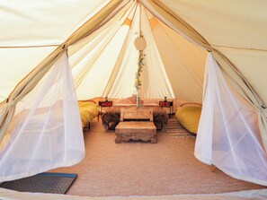 A tent with a bed, a small table, and a hanging decoration. - Stargazing Retreat (Builth Wells)