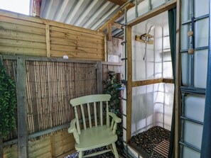 A wooden chair in a corner, a bamboo fence, and a metal-framed window with a shower. - Stargazing Retreat (Builth Wells)