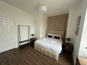 A bedroom with a bed, bedside tables, a wardrobe, and a hanging light fixture. - Cosy 1 BDR top floor apartment in leith (Edinburgh)