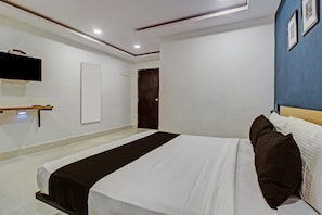 A hotel room with a bed, a flat-screen TV mounted on the wall, and a door with a textured pattern. - Hotel O Qualia Miyapur (Hyderabad)