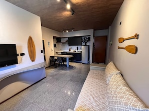 Ein modernes Wohnzimmer mit einer Couch, einem Essbereich mit Tisch und Stühlen, einer Küche mit Schränken und Geräten sowie einem Deckenventilator.