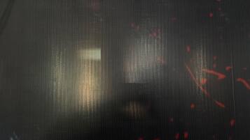 A textured surface with a grid-like pattern and some red speckles.