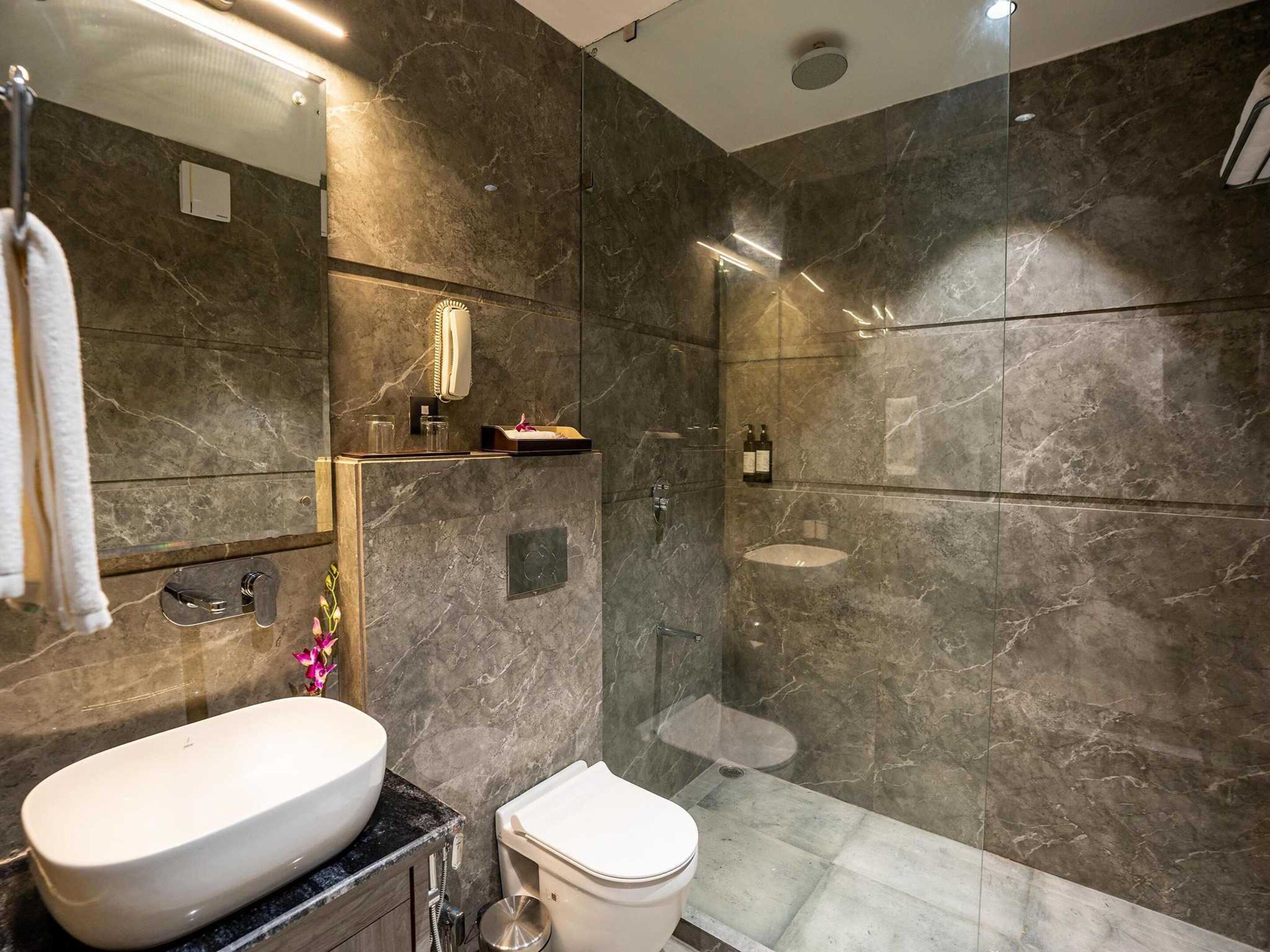 Een moderne badkamer met een groot wit wastafelmeubel, toilet en een douchecabine met glazen wanden.