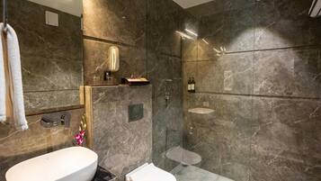 Een moderne badkamer met een groot wit wastafelmeubel, toilet en een douchecabine met glazen wanden.