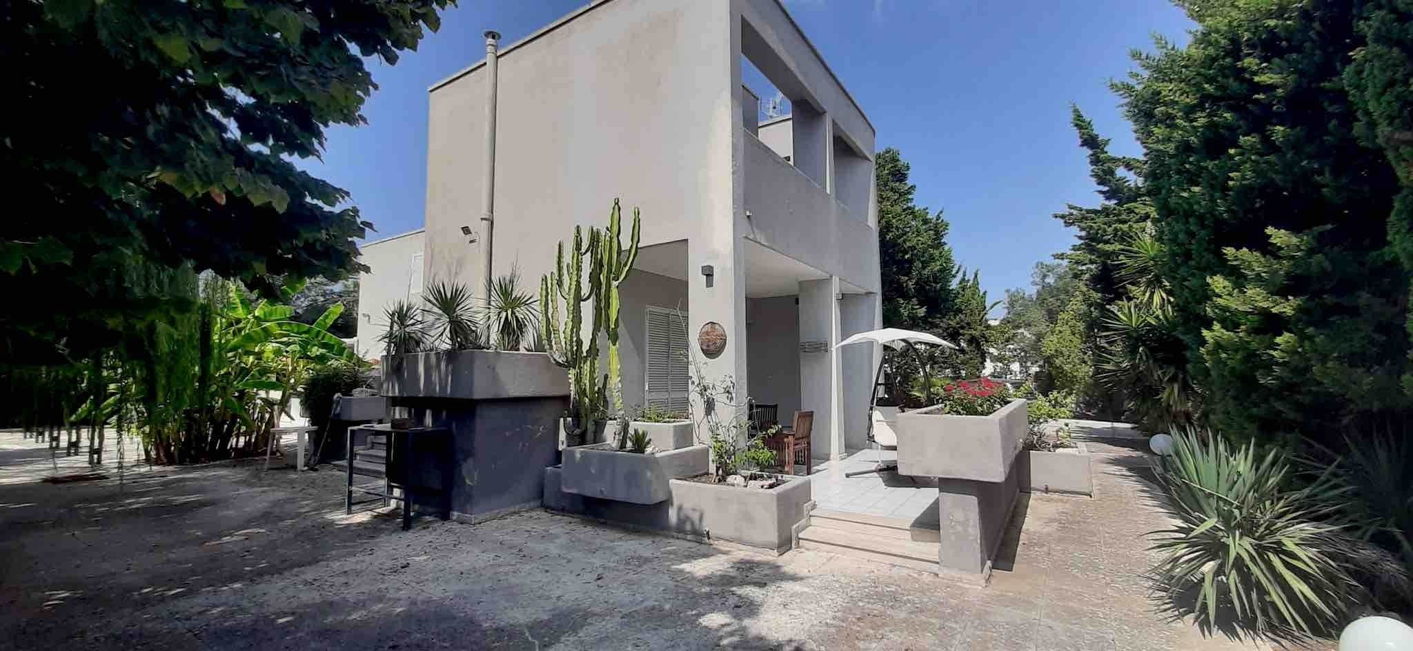 Un bâtiment moderne doté d’un toit plat, entouré de diverses plantes et d’arbres.