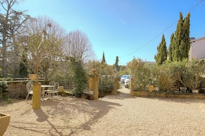 A gravel driveway leading to a white car parked in a driveway with a garden and trees. - The Château du Mas, near Lyon (Bessenay)