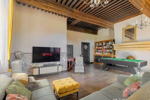 A living room with a flat-screen TV, a pool table, a bookshelf, and a fireplace. - The Château du Mas, near Lyon (Bessenay)
