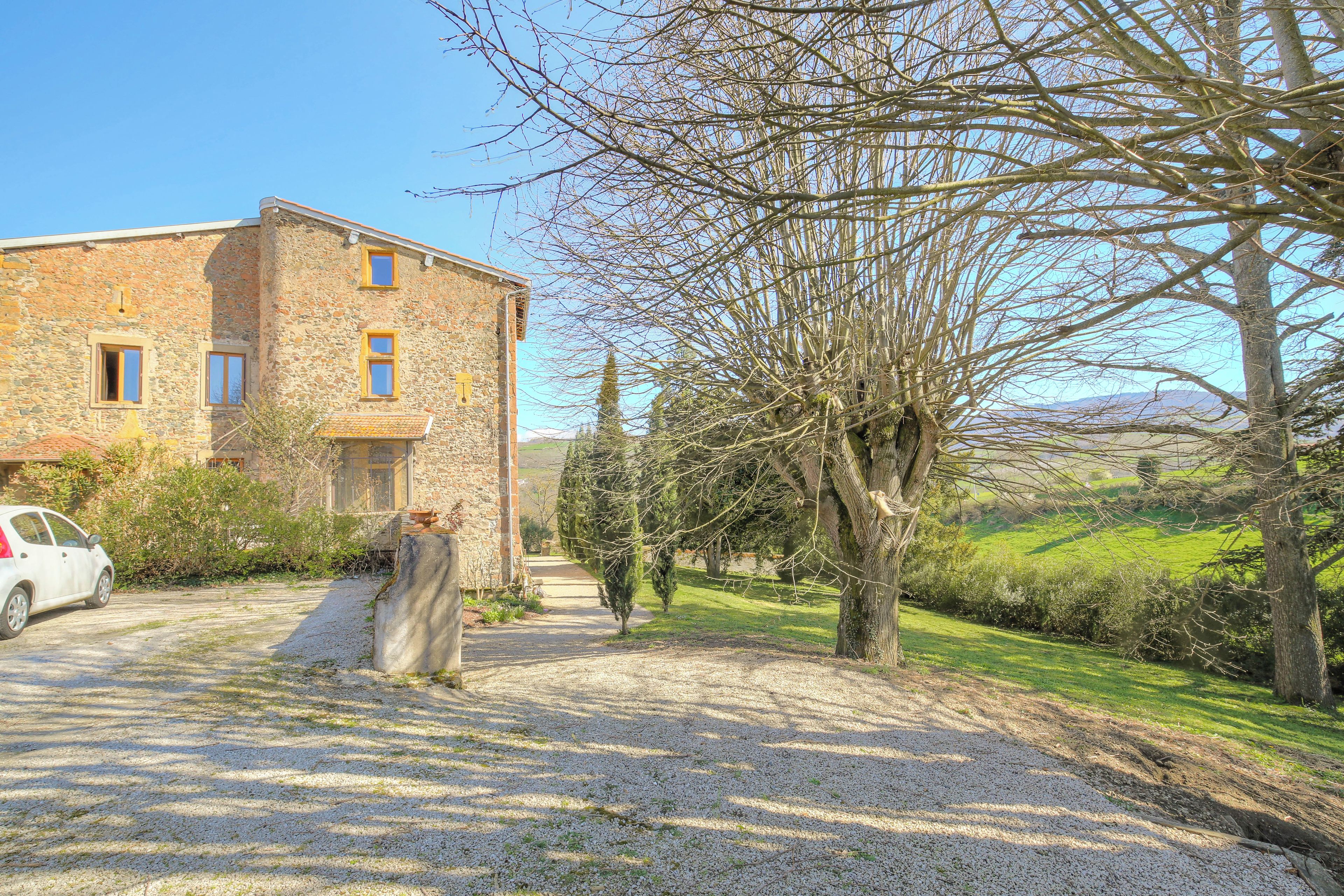 A stone building with a gravel driveway and a parked car.