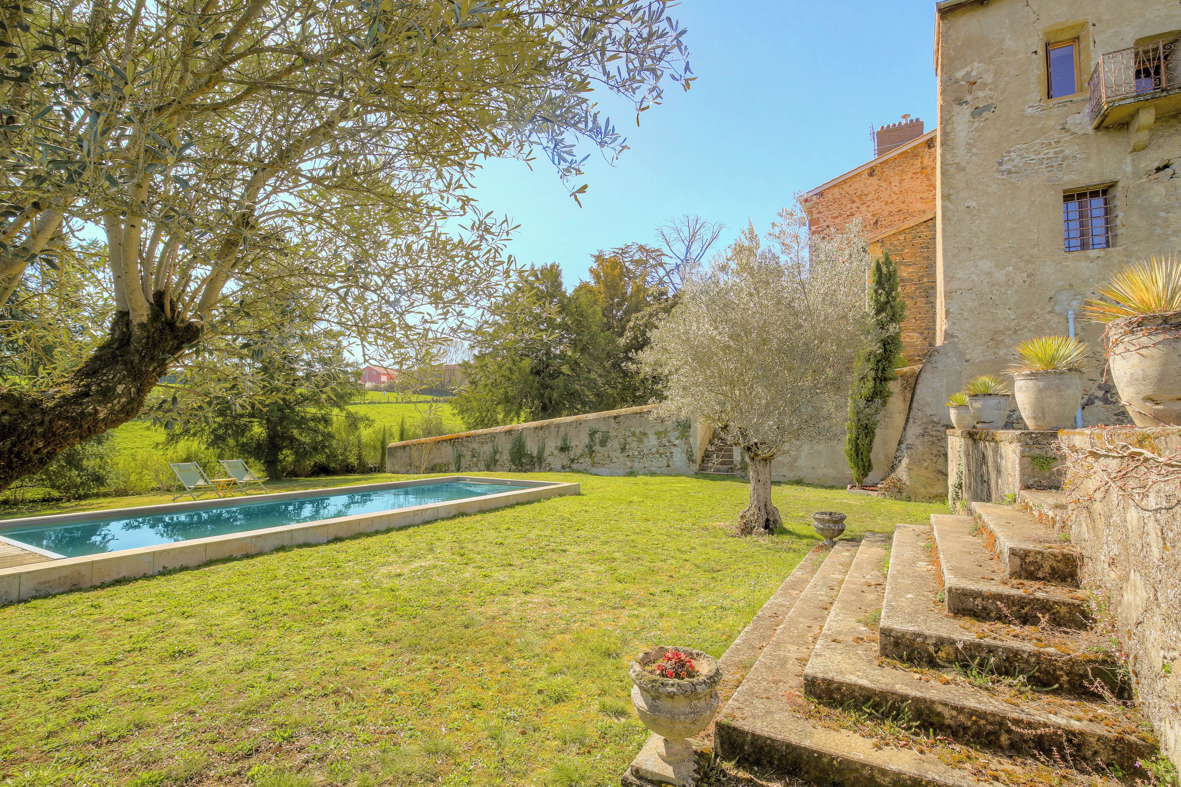 A swimming pool, a grassy lawn, and a stone staircase leading to a building.