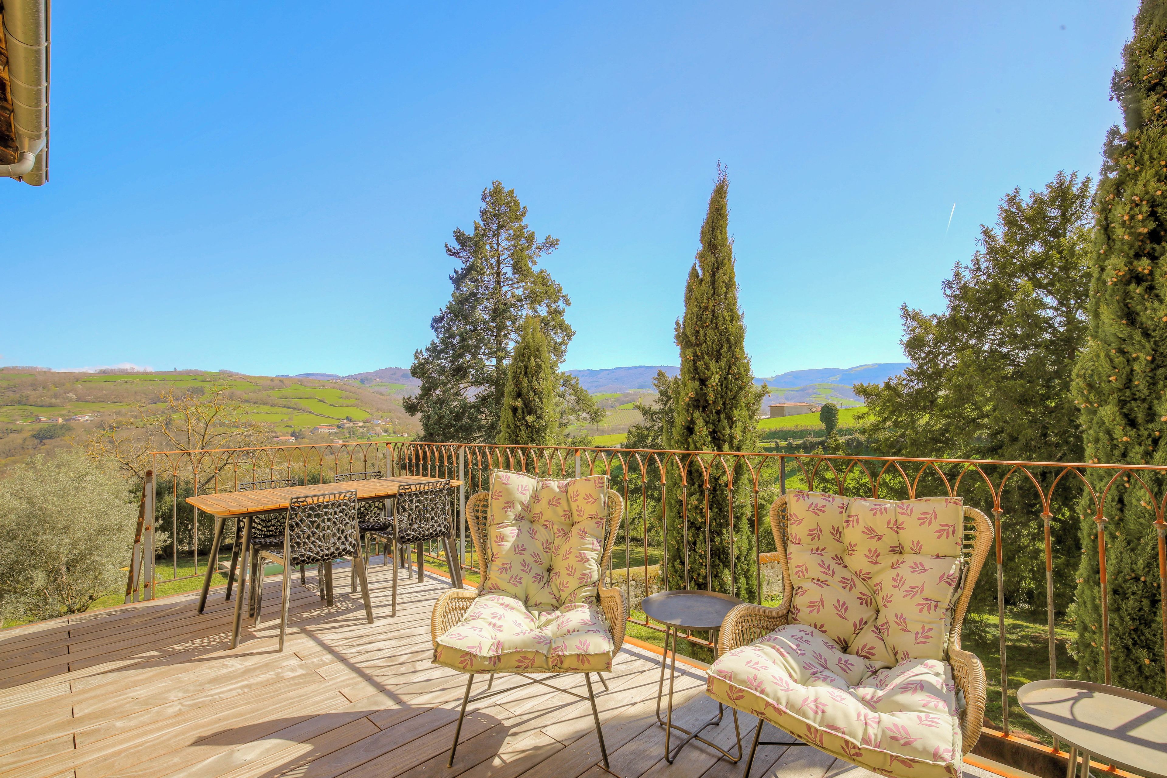 An outdoor deck with a table and chairs, overlooking a scenic landscape.