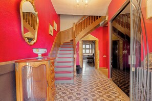 Una scala con ringhiere in legno che conduce a un secondo piano, uno specchio con cornice dorata e un pavimento decorato.
