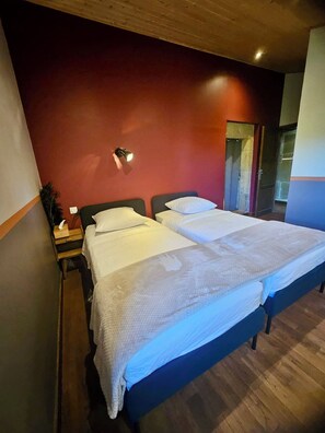 Un letto matrimoniale con testiera in legno, un comodino con lampada e una parete di colore rosso.