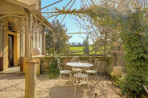 Een terras met een tafel en stoelen, een pergola en uitzicht op een groen landschap.