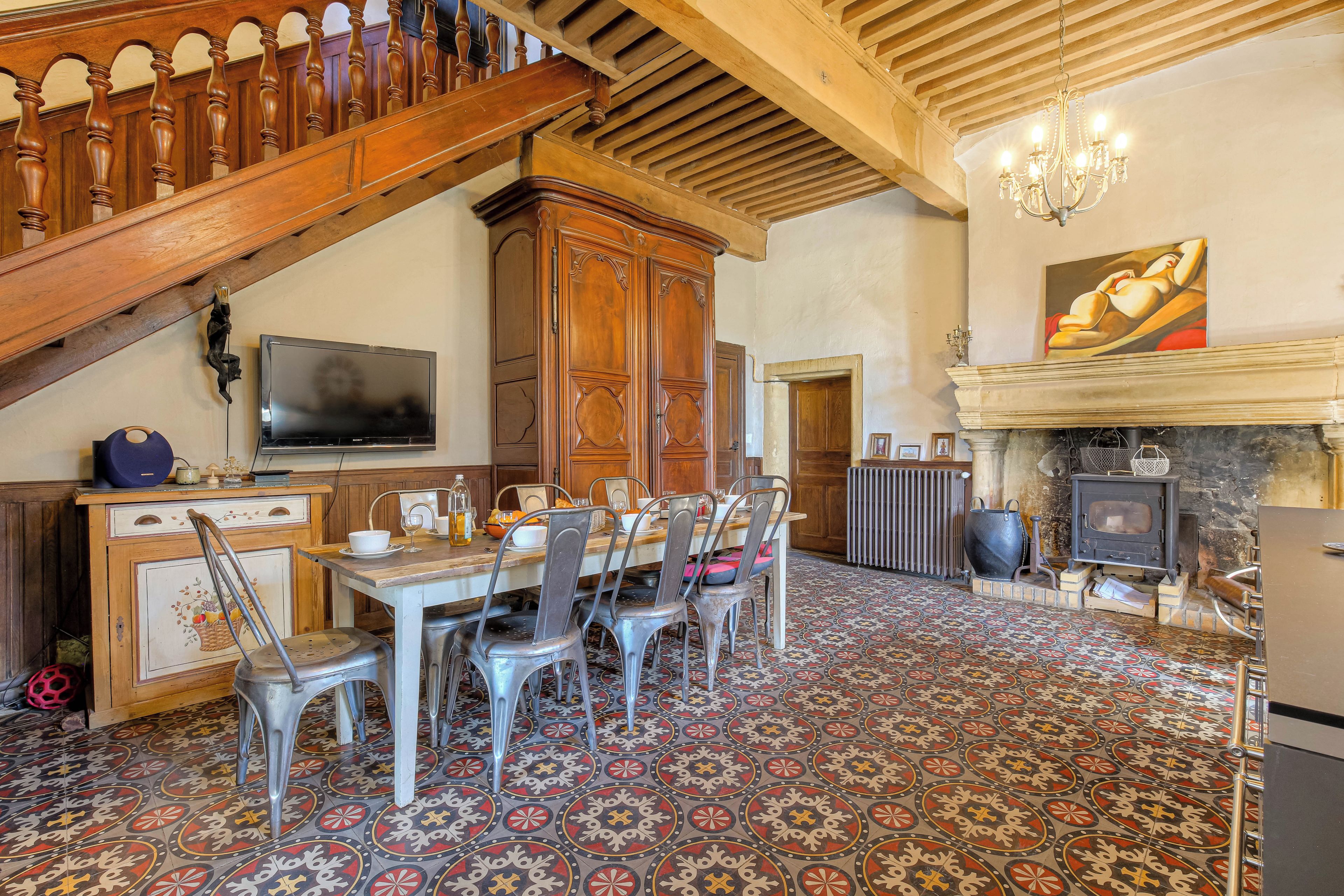 A dining area with a wooden staircase, a fireplace, and a television.